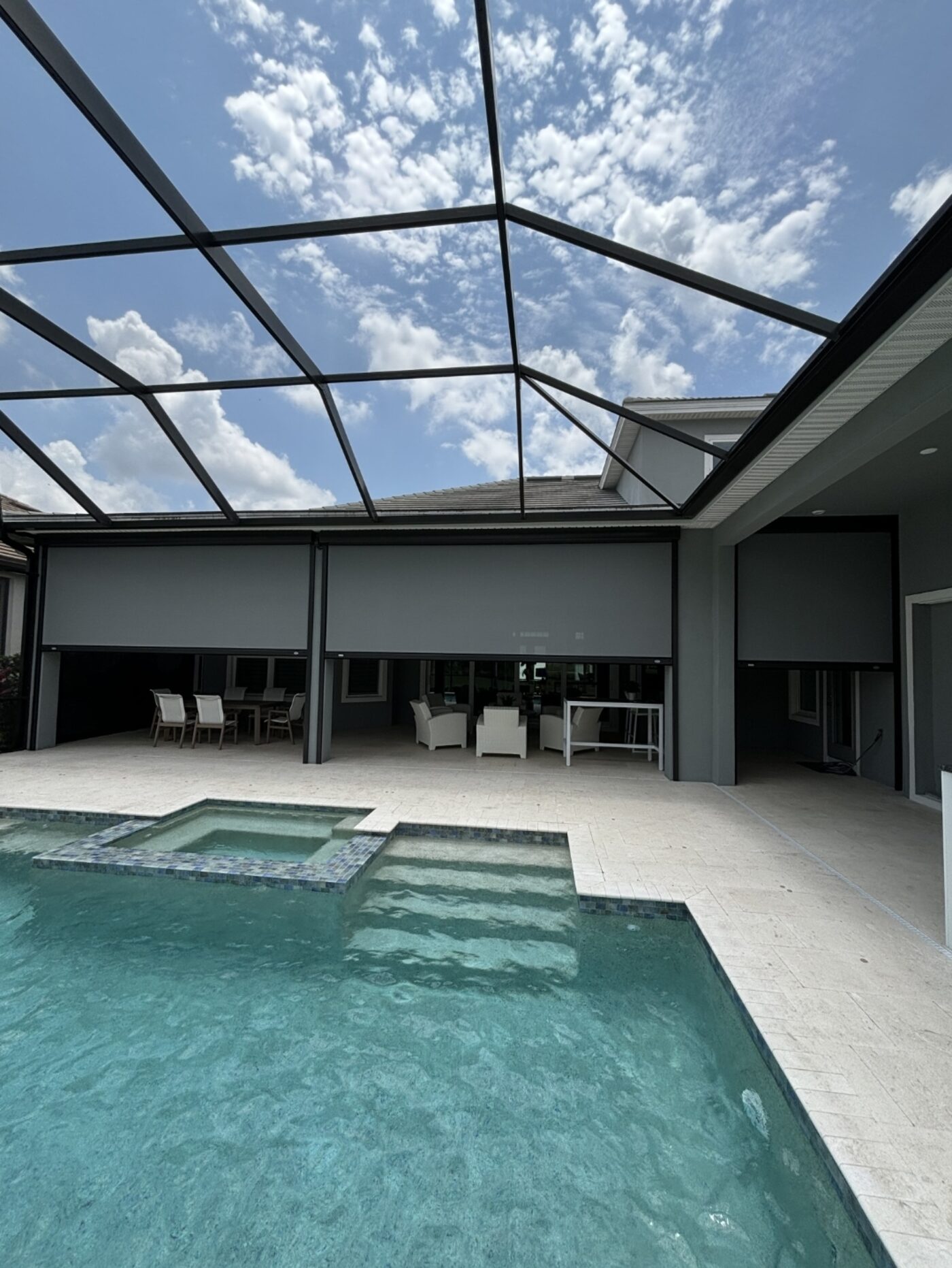 Pool cage with motorized screens deployed across a luxury Florida lanai